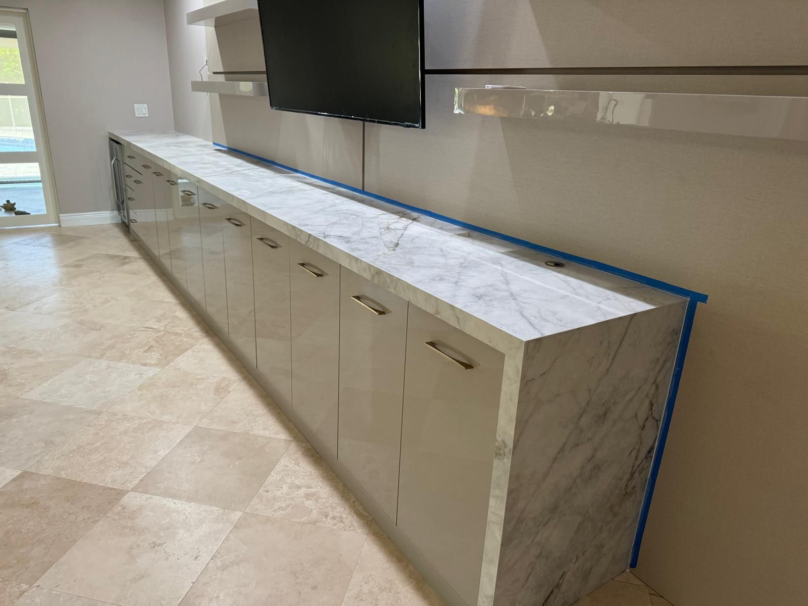 Long porcelain slab countertop media console with waterfall edges, Tampa Bay installation
