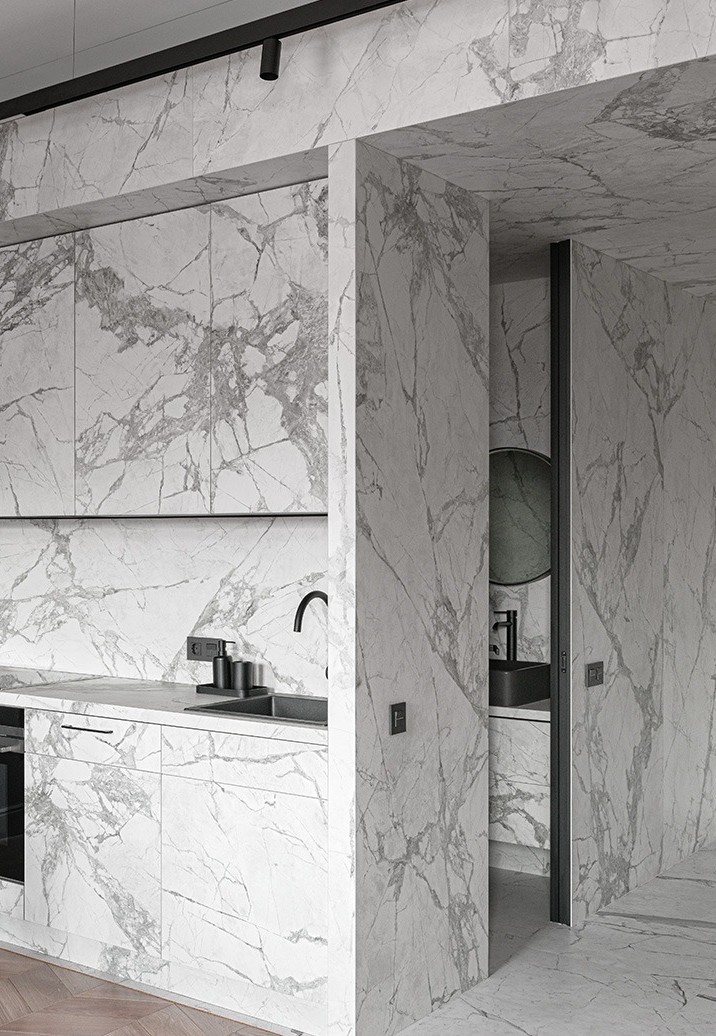 Large-format porcelain slabs in a marble look clad across a kitchen wall and doorway